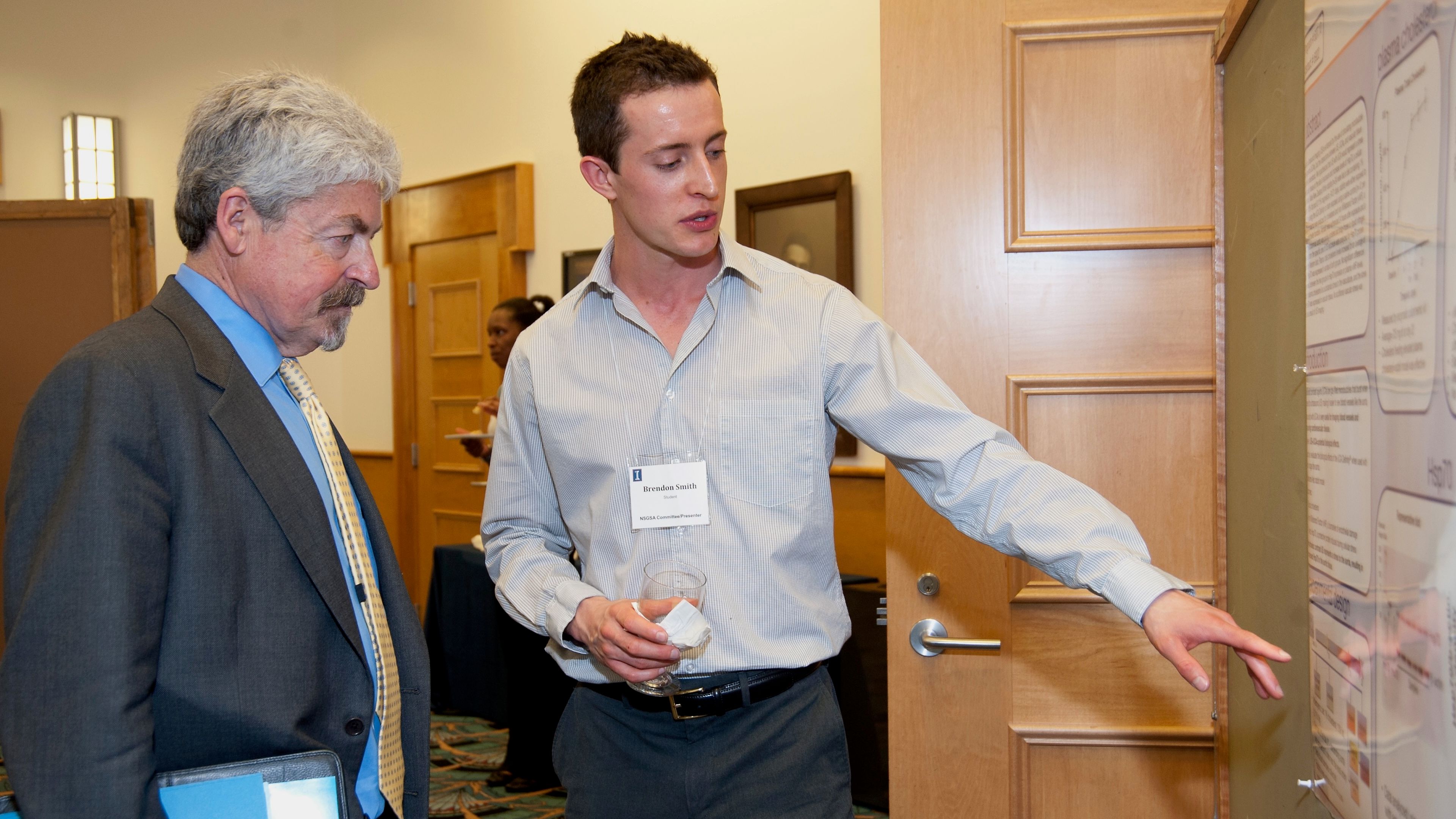 Brendon Smith presenting a research poster to Dr. James O. Hill at the 2012 Nutrition Symposium in the Division of Nutritional Sciences at the University of Illinois at Urbana-Champaign